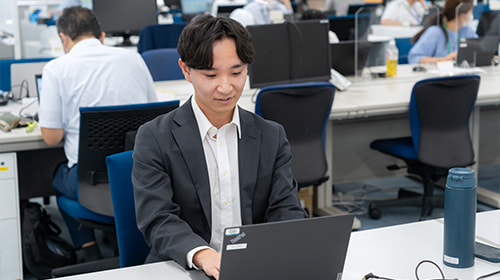 写真 デスクでパソコンを操作するスーツの男性