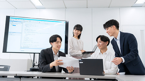写真 パソコンの前で打ち合わせをするスーツの男女