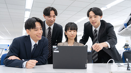 写真 パソコンの前で相談するスーツの男女